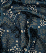 A close-up of draped fabric with a woven geometric pattern in slate blue, beige, and black.