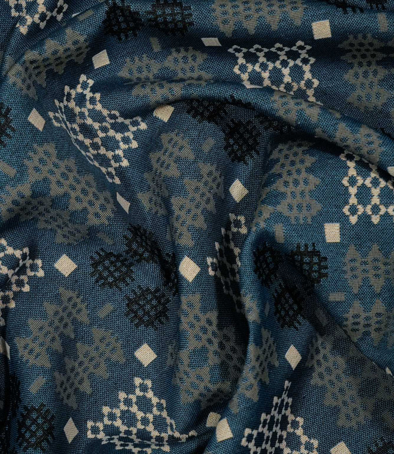 A close-up of draped fabric with a woven geometric pattern in slate blue, beige, and black.