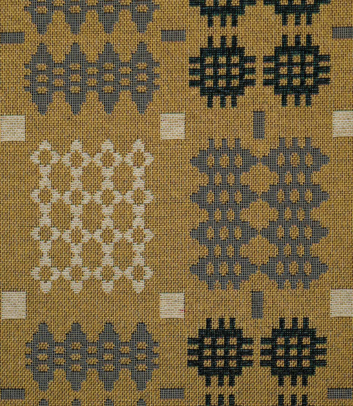 Close-up of Kinfolk fabric showing its textured weave and Scandi-inspired geometric design in charcoal, grey and cream against a mustard yellow ground.