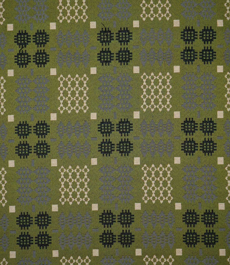 Kinfolk geometric fabric shown flat, with an olive green ground and repeating black, grey and cream woven-style motifs arranged in a structured pattern.