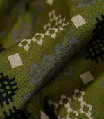 Macro close-up of Kinfolk fabric showing the detailed woven texture and geometric grey, black and cream motifs against an olive green ground.