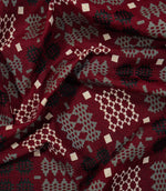 Draped Kinfolk geometric fabric showing its soft folds and repeating black, grey and cream woven-style pattern on a rich red ground.