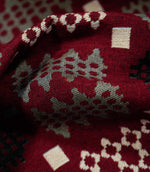Macro close-up of Kinfolk fabric showing the detailed weave, with soft grey and cream geometric motifs standing out against the deep red background.