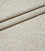 Larkspur Linen Look fabric arranged in neat folds, showing the repeating cream and soft beige botanical pattern and natural-looking woven texture.