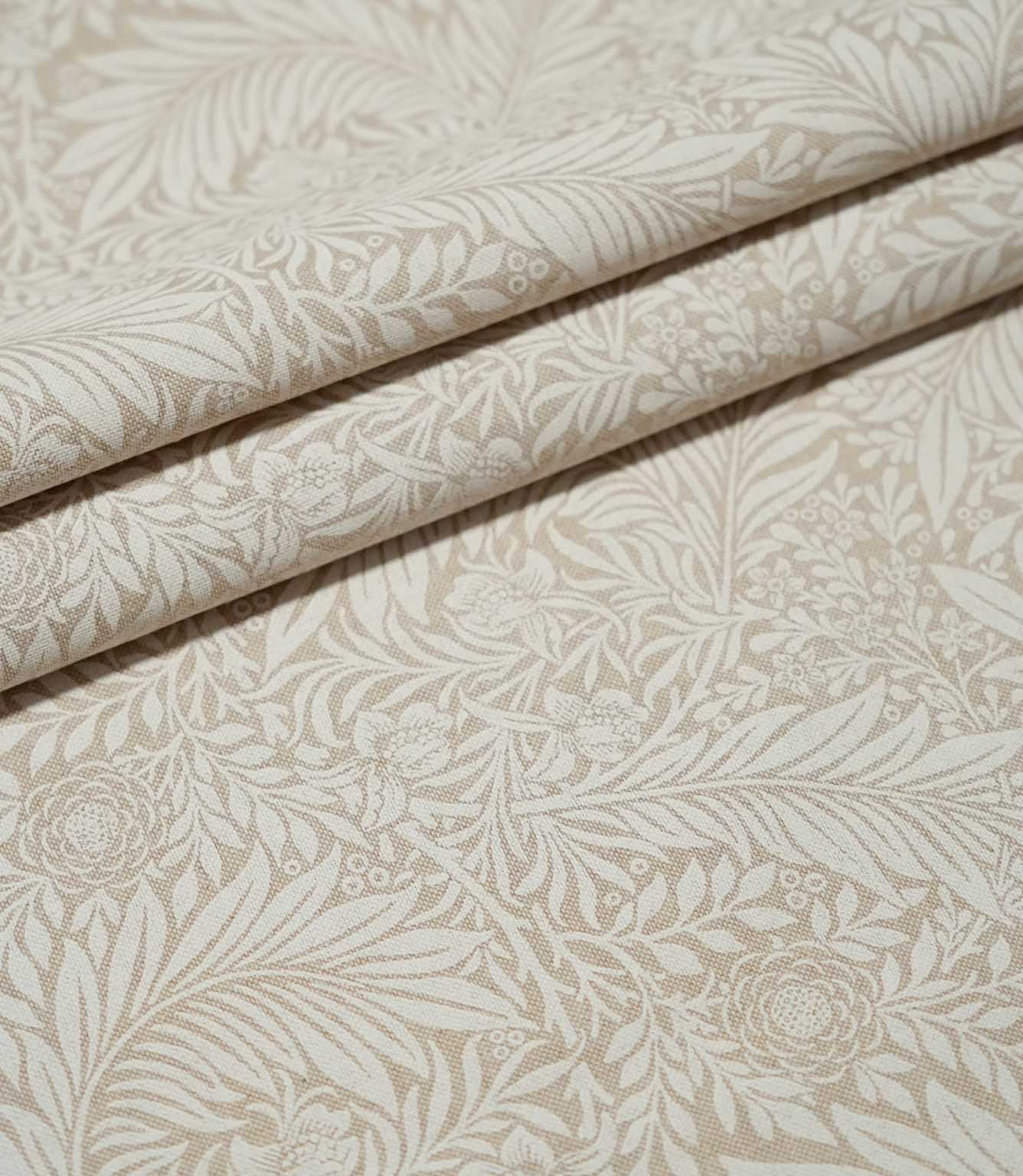 Larkspur Linen Look fabric arranged in neat folds, showing the repeating cream and soft beige botanical pattern and natural-looking woven texture.