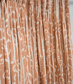Little Bracken Rust fabric gathered into soft curtain folds, featuring an off-white botanical fern and foliage design on a warm rust orange background.