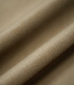 Lois Velvet Oat fabric arranged in gentle folds, showcasing its warm beige colour, softly textured velvet surface and fine linear detailing as the fabric catches the light.