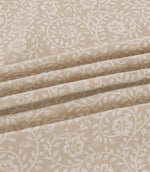 Close-up of Marion Quaker fabric draped in soft folds, highlighting the intricate ivory embroidered flowers, trailing vines and delicate foliage on a natural beige woven background.