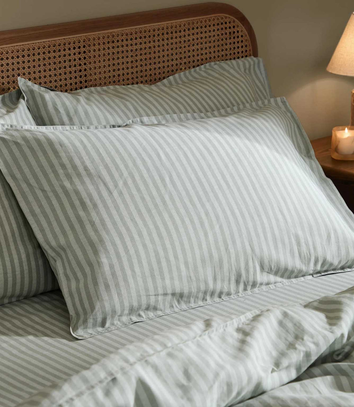 Close-up of Marlow Stripe pillowcases and duvet cover in Artichoke/Sage, showing the fine sage green and off-white striped pattern and softly relaxed fabric finish.