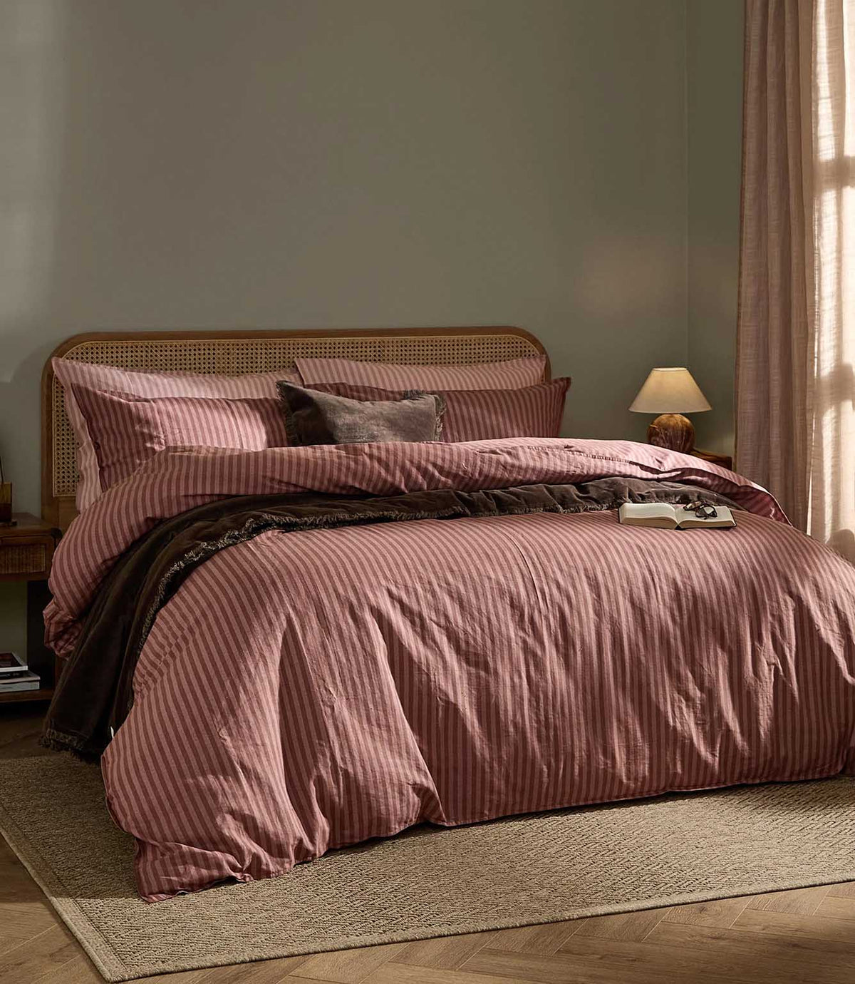 Marlow Stripe Duvet Cover Set in Chocolate/Rosewood, styled on a bed with warm rose pink and chocolate brown stripes, dark brown throw and natural cane headboard.