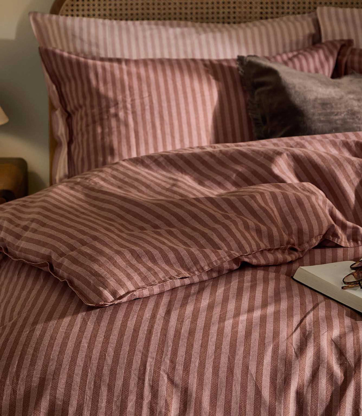 Close-up of Marlow Stripe bedding in Chocolate/Rosewood showing the fine rose pink and chocolate brown striped pattern and softly relaxed fabric texture.