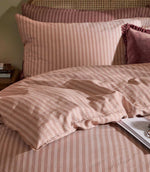 Close-up of Marlow Stripe bedding showing soft blush pink and rose vertical stripes, coordinating pillowcases and the gently crumpled fabric texture.