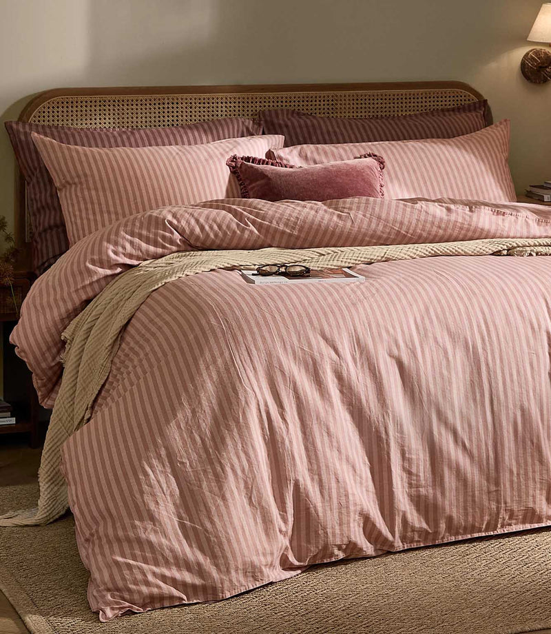 Marlow Stripe blush pink and rose duvet cover set styled with matching striped pillowcases, a textured neutral throw and rose accent cushion.