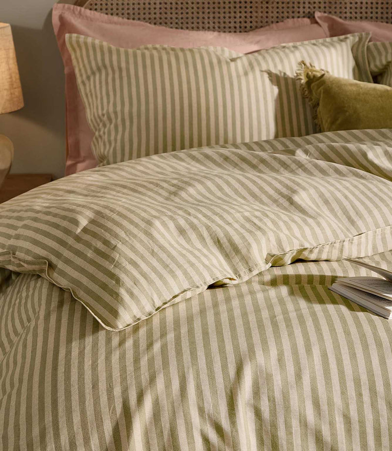Close-up of Marlow Stripe bedding in olive green and cream, showing the fine striped pattern, coordinating pillowcases and softly relaxed fabric texture.