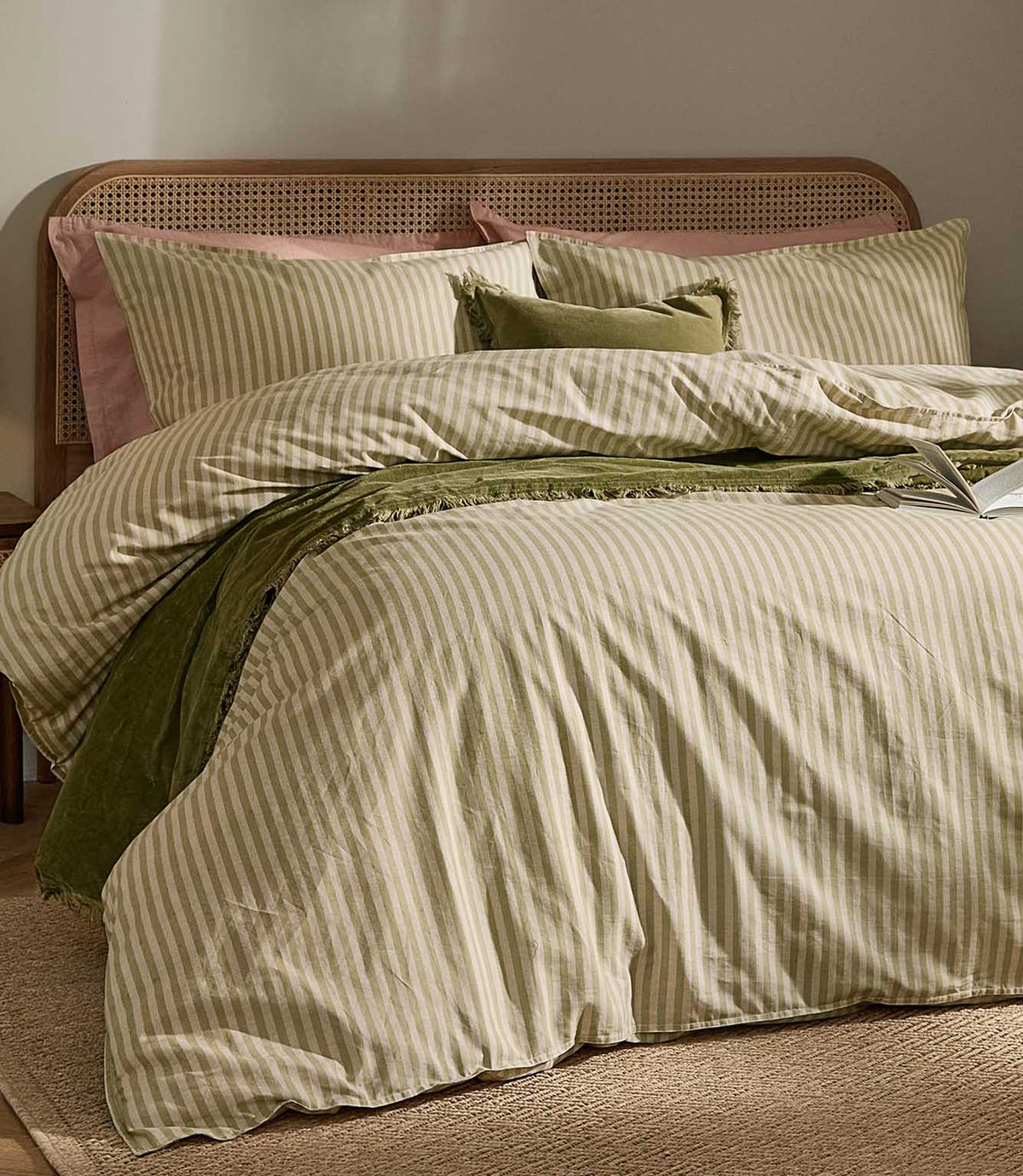Marlow Stripe olive green and cream duvet cover set styled with matching striped pillowcases, green velvet accents and a natural cane headboard.