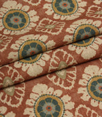 Folded terracotta red fabric with repeating floral medallion design, suitable for curtains, blinds and upholstery projects.