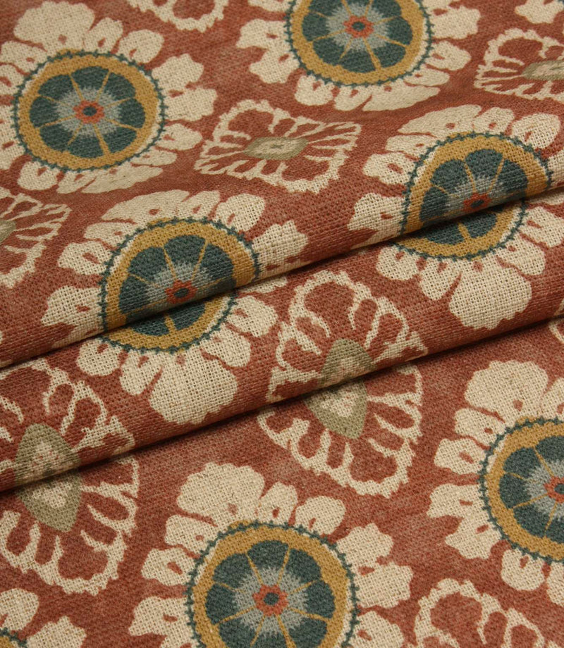 Folded terracotta red fabric with repeating floral medallion design, suitable for curtains, blinds and upholstery projects.