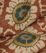 Close-up detail of terracotta and blue floral medallion fabric on a rustic woven base cloth.