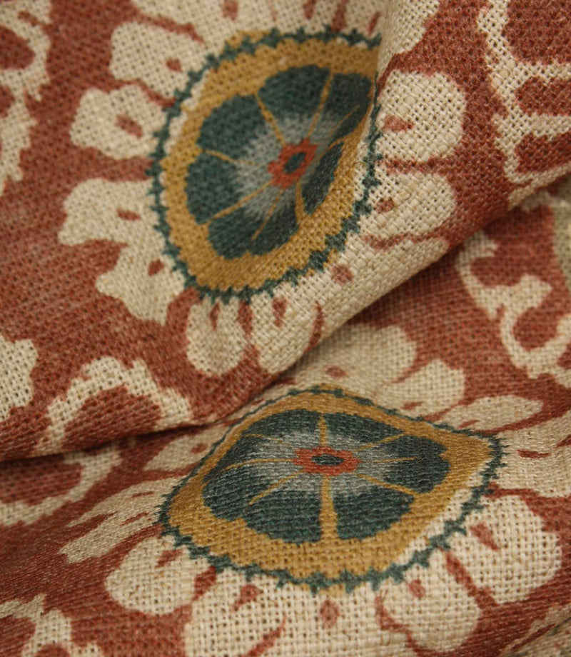 Close-up detail of terracotta and blue floral medallion fabric on a rustic woven base cloth.