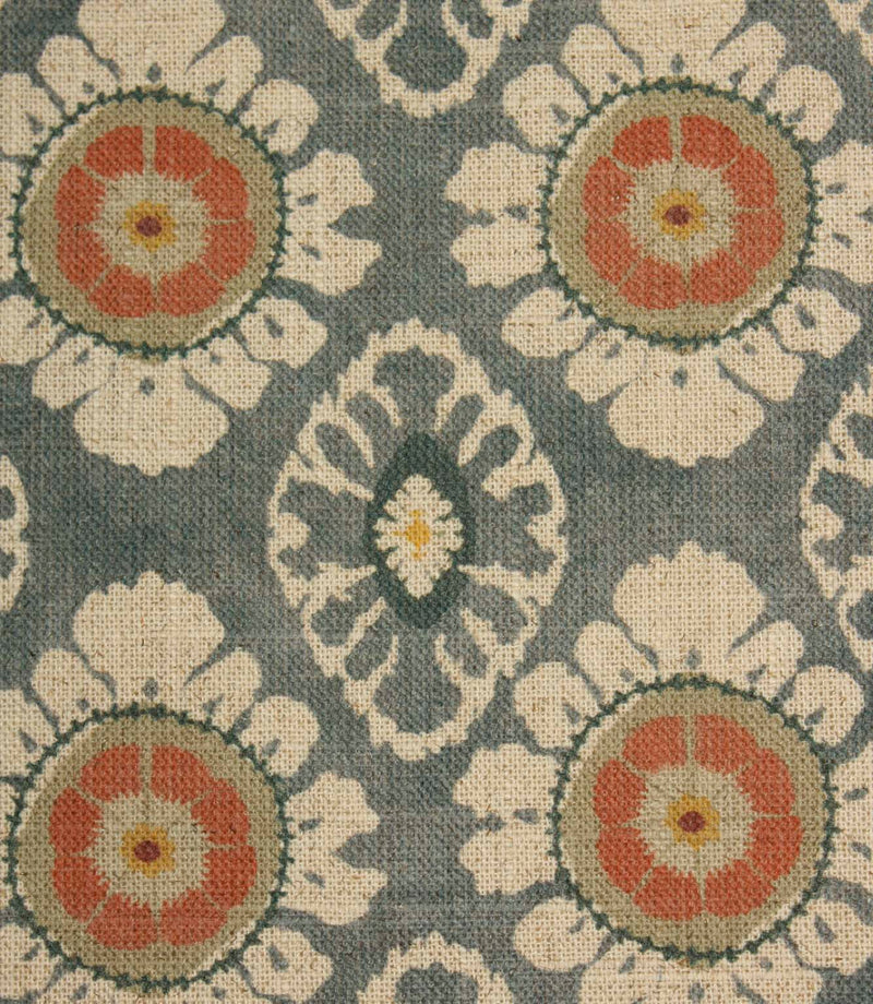 Close-up of blue grey vintage-style floral fabric with coral medallions and cream ornamental motifs.