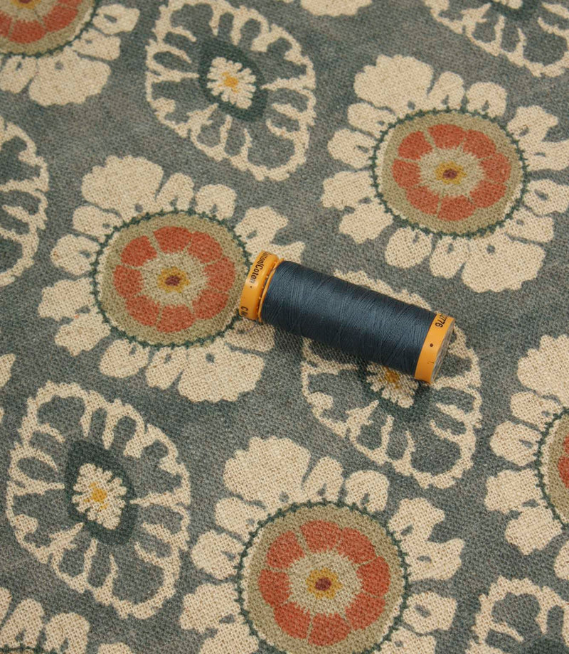 Blue grey patterned fabric styled with matching thread spool to highlight colour tones and textured woven finish.