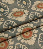 Folded blue grey floral fabric featuring repeating medallion motifs and a soft linen-look texture.