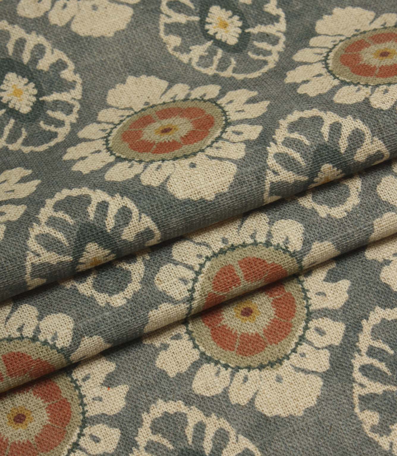 Folded blue grey floral fabric featuring repeating medallion motifs and a soft linen-look texture.