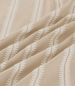 Close-up of Meschutt Quaker fabric draped in gentle folds, highlighting raised ivory zigzag embroidery, fine beige central stitching and the natural woven texture of the fabric.