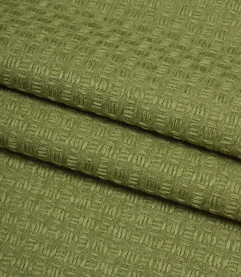 Folded Nessa woven fabric in green, showing the structured geometric texture and quality finish.