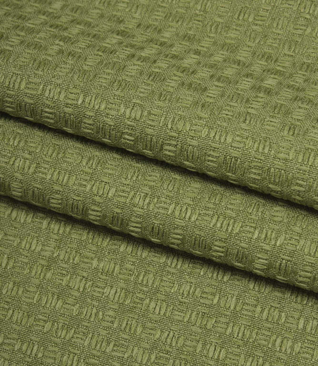 Folded Nessa woven fabric in green, showing the structured geometric texture and quality finish.