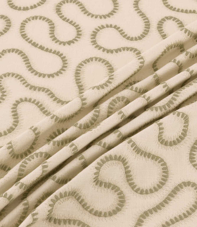 Close-up of Orient Willow fabric draped in gentle folds, showing olive green embroidered wavy lines on a natural cream woven background.