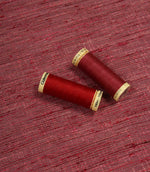 Otaru woven plain fabric with matching red thread spools, showing the fabric texture and colour coordination.