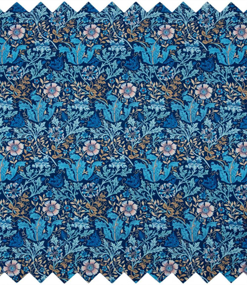 Close-up of woodblock floral fabric with an intricate navy blue background, turquoise and blue foliage, soft pink flowers and trailing gold leaves.