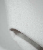 Detailed close-up of Palermo Marble light grey upholstery fabric folded over itself, revealing its softly brushed surface, fine mottled fibres and smooth, rounded fold.