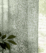Close-up of Perrie Leaf sheer curtain fabric in forest green and soft white, showing the lightweight woven texture and delicate trailing leaf pattern.