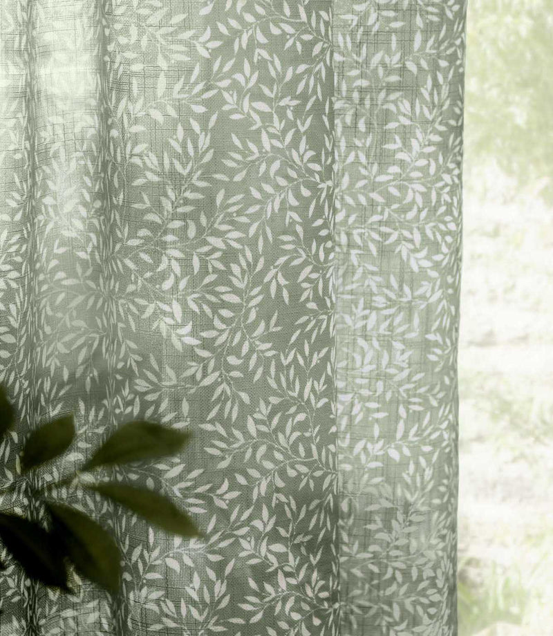 Close-up of Perrie Leaf sheer curtain fabric in forest green and soft white, showing the lightweight woven texture and delicate trailing leaf pattern.