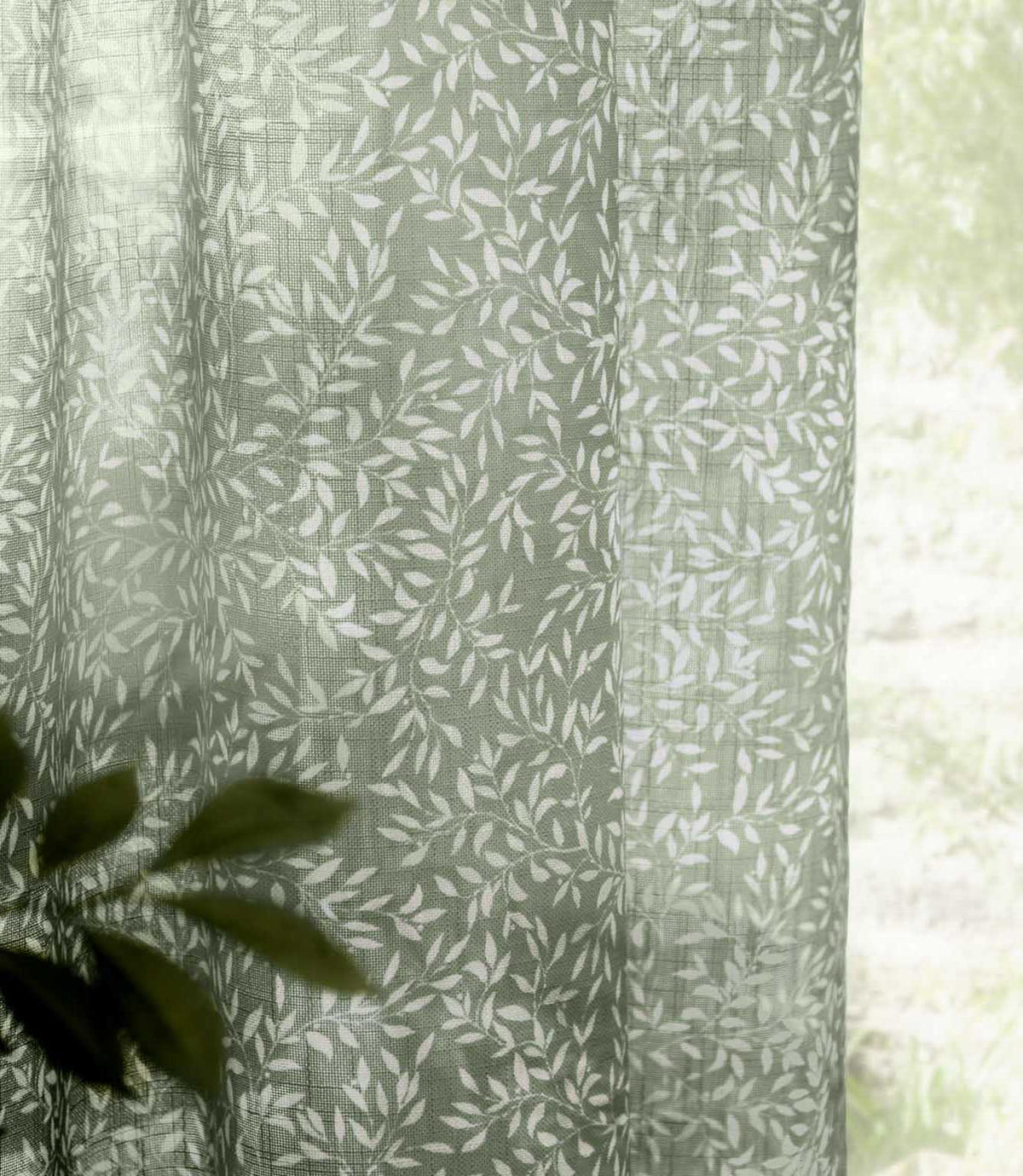 Close-up of Perrie Leaf sheer curtain fabric in forest green and soft white, showing the lightweight woven texture and delicate trailing leaf pattern.