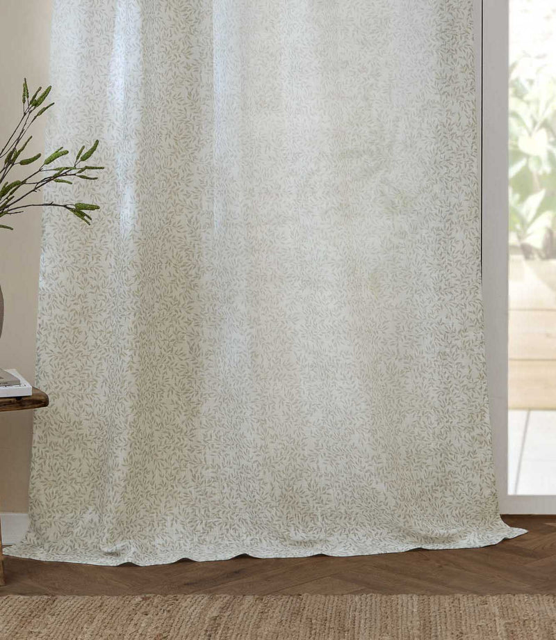 Full-length Perrie Leaf sheer curtain in natural cream and soft beige, showing the delicate leaf design and light-filtering fabric draping onto a wooden floor.