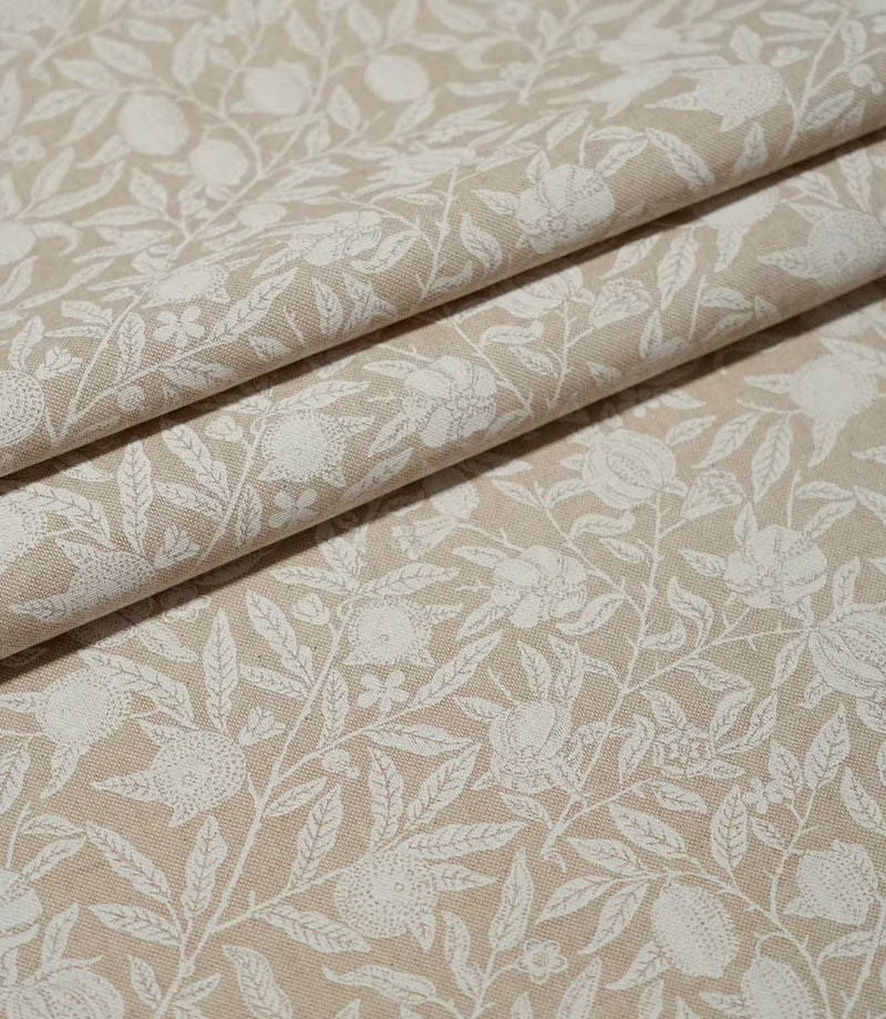 Pomegranate Linen Look William Morris fabric arranged in folds, showing the beige and cream botanical pattern of fruit, flowers and trailing foliage.