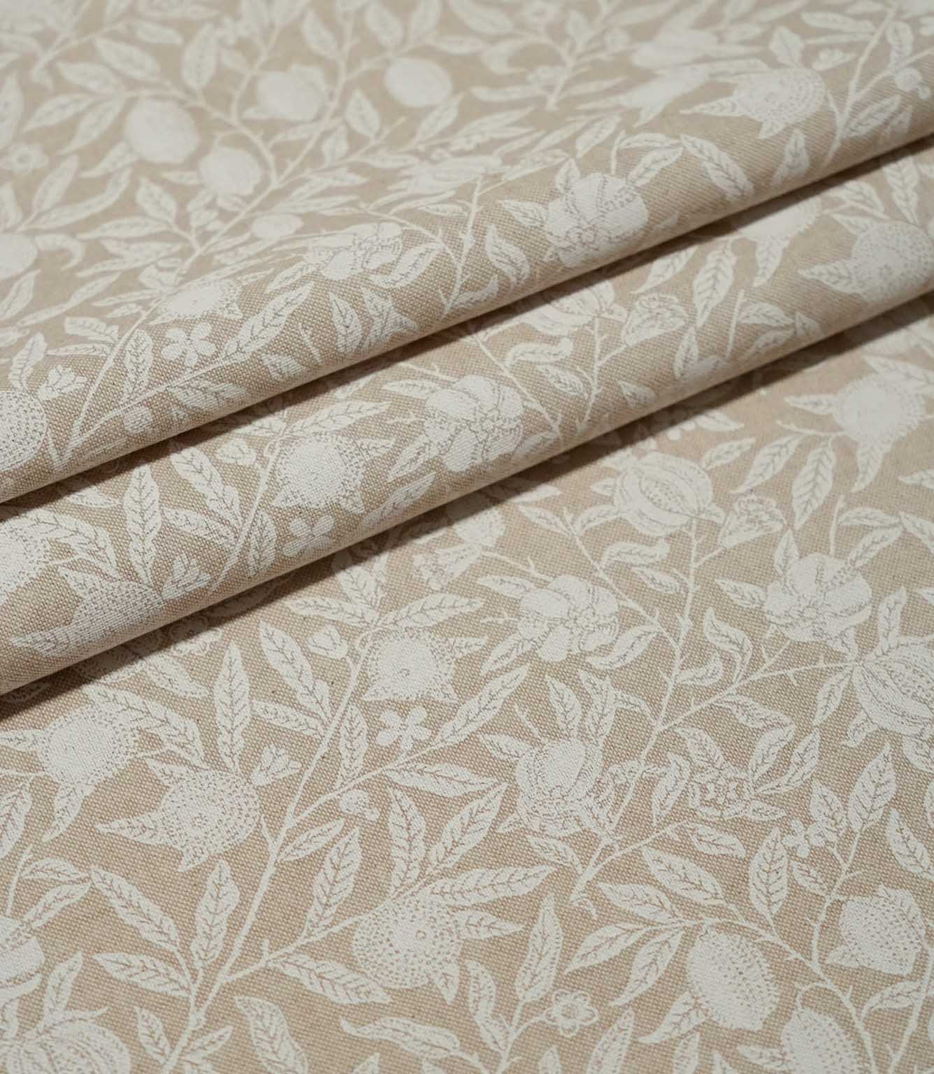 Pomegranate Linen Look William Morris fabric arranged in folds, showing the beige and cream botanical pattern of fruit, flowers and trailing foliage.