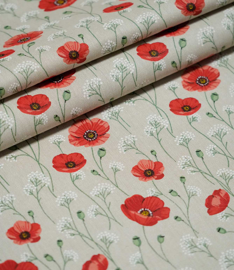 Poppy Trail Red floral fabric arranged in overlapping folds, displaying its scattered red poppies, green botanical stems and white wildflower details.