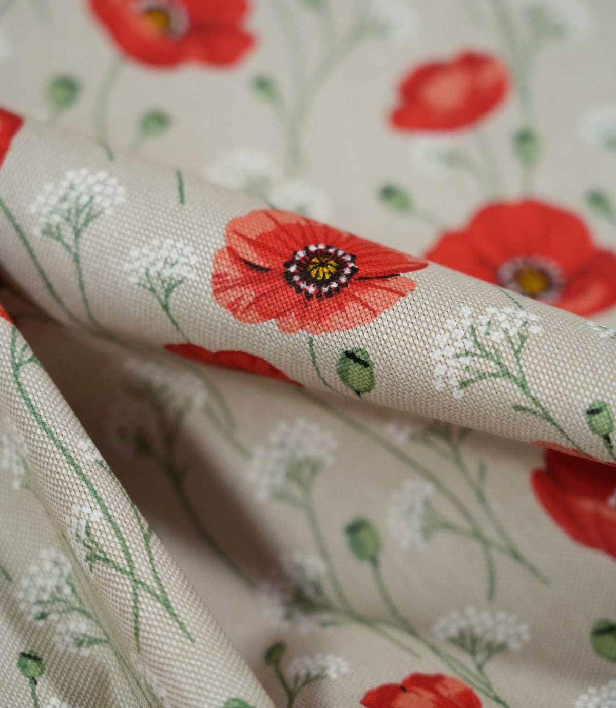 Detailed close-up of Poppy Trail Red floral fabric showing a coral poppy with a dark centre, fine green stems and white wildflowers across the textured woven surface.