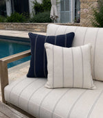 Outdoor pool setting with a sofa featuring striped outdoor cushions in woven fabric