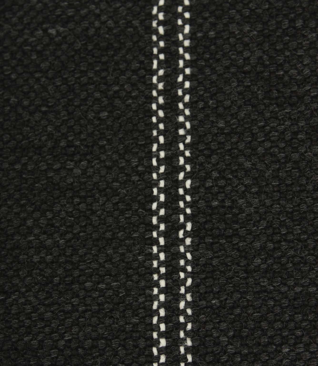 Close-up detail of black textured woven fabric featuring narrow white stitched stripe detailing.