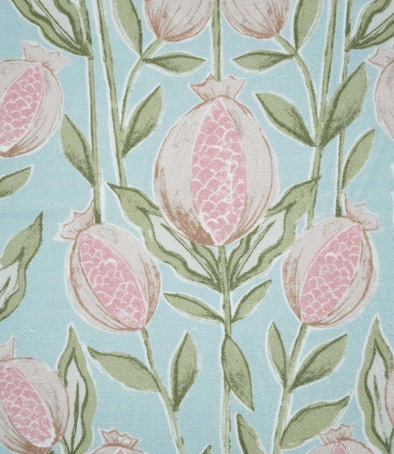Close-up of Rithani Robin's Egg fabric showing detailed pink pomegranate seeds within cream fruit, surrounded by sage green leaves and stems against a pale blue background.