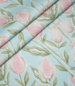 Rithani Robin's Egg fabric arranged in overlapping folds, featuring illustrated pink pomegranates, cream fruit outlines and sage green botanical leaves on a pale blue background.