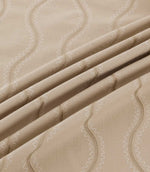 Close-up of Riverhead Quaker fabric draped into gentle folds, revealing textured beige embroidered stripes and fine ivory scalloped stitching on a natural taupe background.