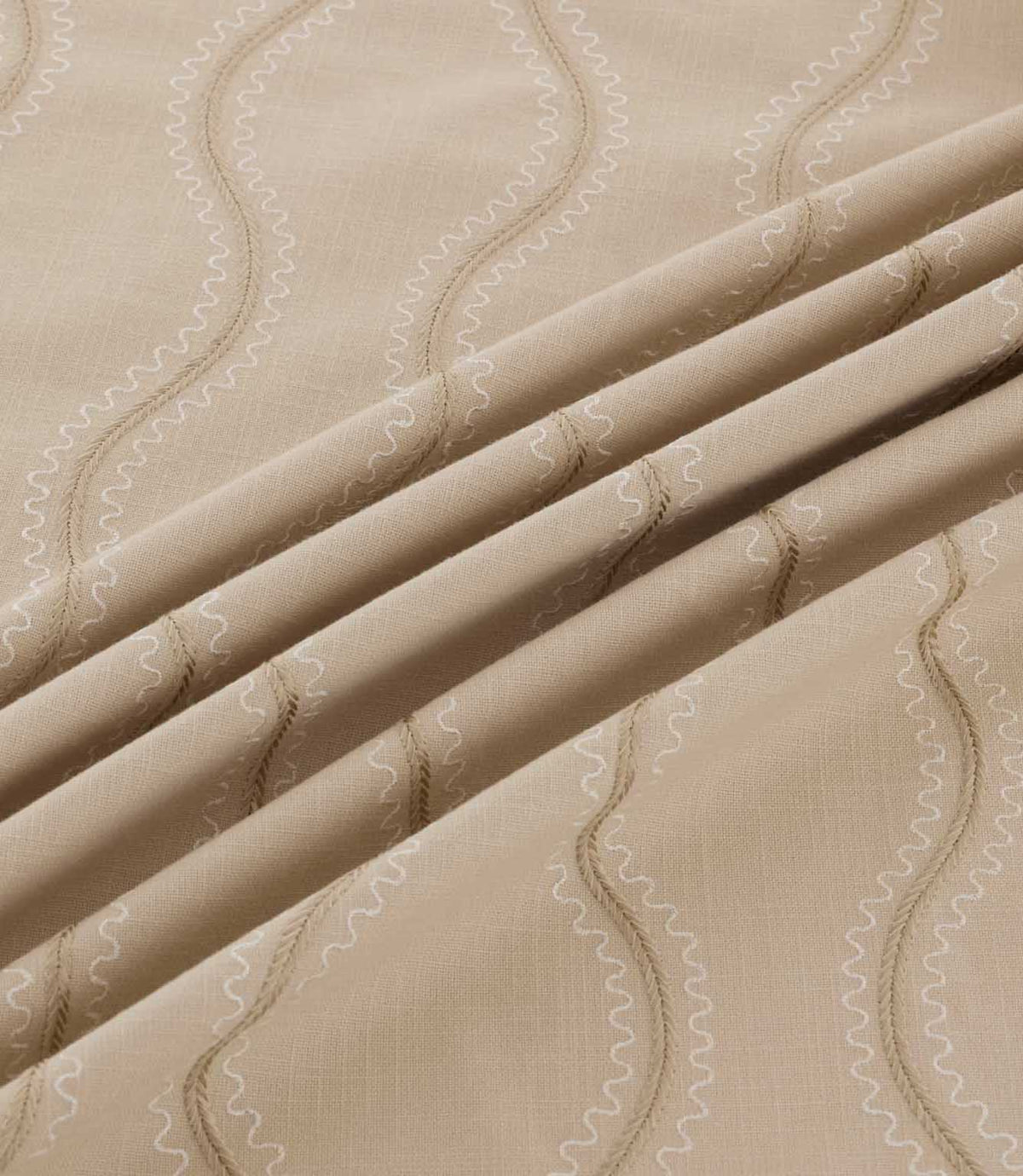 Close-up of Riverhead Quaker fabric draped into gentle folds, revealing textured beige embroidered stripes and fine ivory scalloped stitching on a natural taupe background.