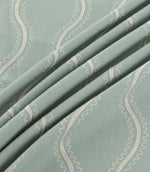 Riverhead Saltwater embroidered fabric gathered into soft folds, showcasing raised ivory wavy stripes, delicate scalloped edges and a muted seafoam blue-green base.