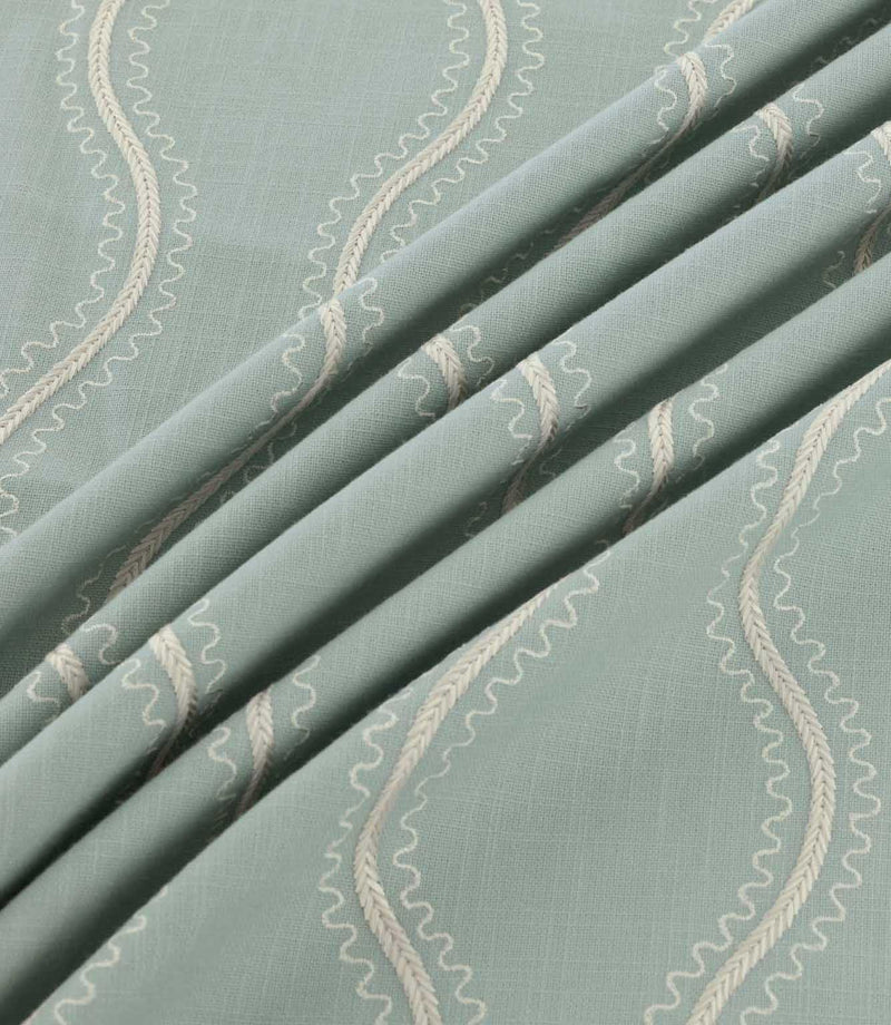 Riverhead Saltwater embroidered fabric gathered into soft folds, showcasing raised ivory wavy stripes, delicate scalloped edges and a muted seafoam blue-green base.